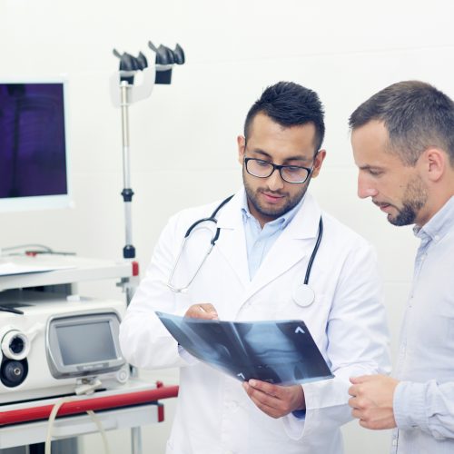 Patient and doctor looking at knee x-ray result in clinical office